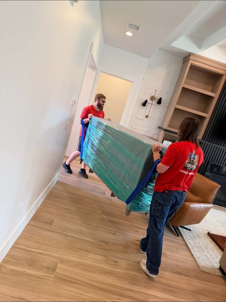 Top Boss movers carrying a wrapped piece of furniture through a home